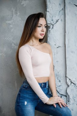 Mavi jeans ve bej t-shirt güzel genç kadın portresi. Lüks daireler iç duvara yakın duran genç model