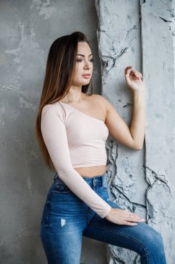 Mavi jeans ve bej t-shirt güzel genç kadın portresi. Lüks daireler iç duvara yakın duran genç model