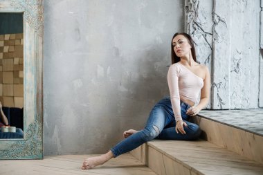 Mavi jeans ve bej t-shirt güzel genç kadın portresi. Lüks daireler iç katında oturan genç modeli