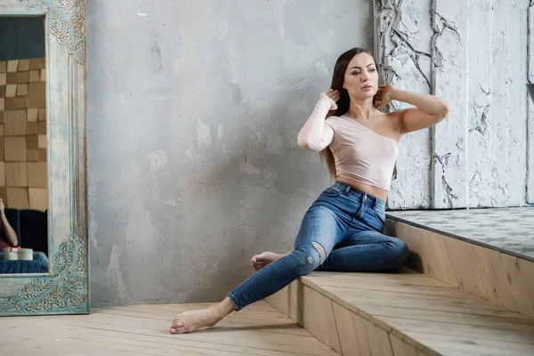 Mavi jeans ve bej t-shirt güzel genç kadın portresi. Lüks daireler iç katında oturan genç modeli