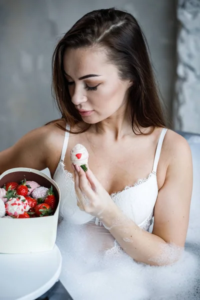 Beyaz iç çamaşırı güzel genç kadın portresi. Model banyo ve tatlılar yemek