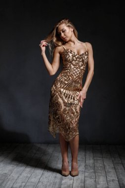 Stüdyoda şık altın elbise ayakta güzellik sarışın kadın moda portre, gri arka plan 