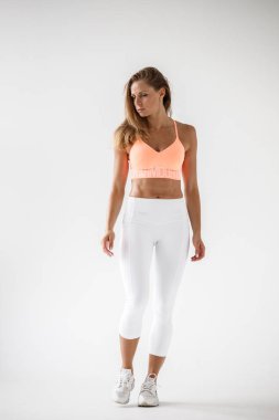 Spor giysileri, beyaz duvar arka planda güzellik modeli ayakta sportif genç kadın stüdyo çekim  