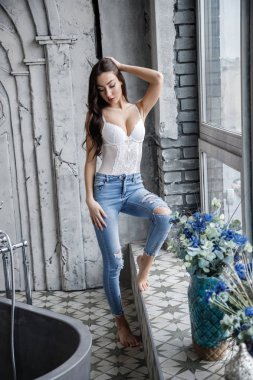 Beyaz iç çamaşırı ve mavi kot giyen güzel esmer kadın stüdyo portresi. Charming güzellik modeli daire iç poz  