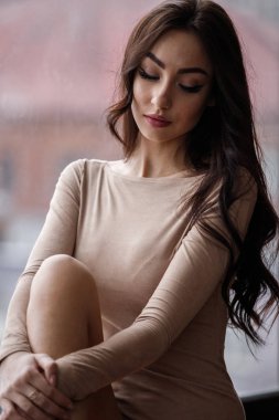 Bej giysi giyen güzel esmer kadın stüdyo portresi. Charming güzellik modeli daire iç poz  