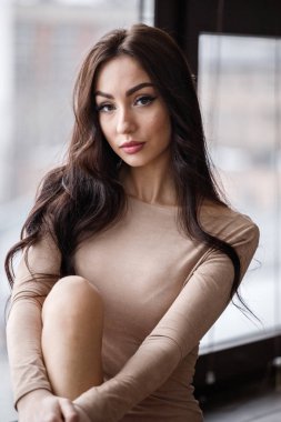 Bej giysi giyen güzel esmer kadın stüdyo portresi. Charming güzellik modeli daire iç poz  