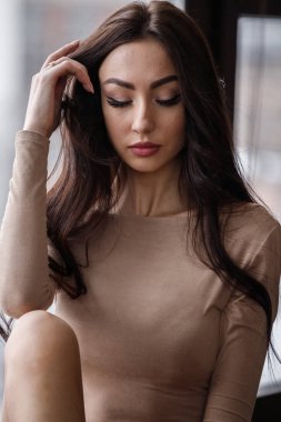 Bej giysi giyen güzel esmer kadın stüdyo portresi. Charming güzellik modeli daire iç poz  