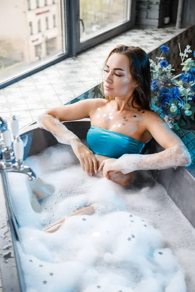 青いランジェリーで現代的なバスルームのインテリアでお風呂に入る美しさの若い女性のクローズアップ肖像画 — ストック写真