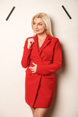 Bej duvar arka plan üzerinde duran kırmızı ceketli güzellik sarışın kadın Portresi 