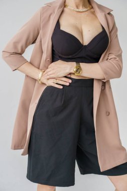 Beyaz arka planda izole edilmiş seksi sarışın modelin şık bir portresi. Bej ceketli genç bir manken ve stüdyoda poz veren siyah günlük kıyafetler.