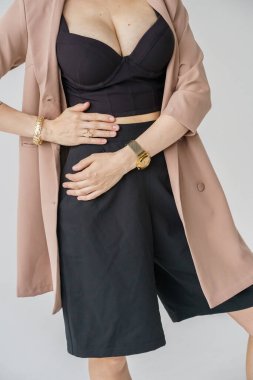 Beyaz arka planda izole edilmiş seksi sarışın modelin şık bir portresi. Bej ceketli genç bir manken ve stüdyoda poz veren siyah günlük kıyafetler.