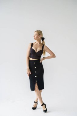 Beyaz arka planda izole edilmiş seksi sarışın modelin şık bir portresi. Stüdyoda poz veren siyah günlük kıyafetler giyen genç bir manken.