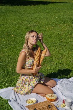 Yazlık giysiler içinde sarışın güzel bir kadının açık hava portresi. Yeşil Park 'taki piknikte dinlenen model.