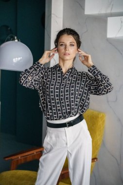 Sarı koltuğun yanında duran genç ve güzel bir kadın. Gayri resmi giyinmiş esmer bir kadın portresi. 