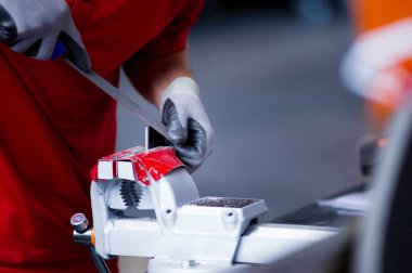 eldivenli eller bir yardımcı lıkta kenetlenmiş metal bir iş parçası üzerinde çalışır