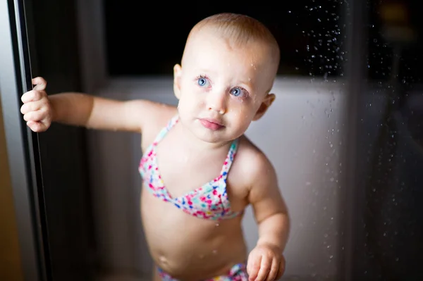 Маленька дівчинка в купальнику дивиться з душу — стокове фото