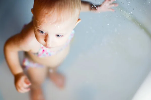 Mädchen im Badeanzug steht in der Dusche und genießt Wasser — Stockfoto