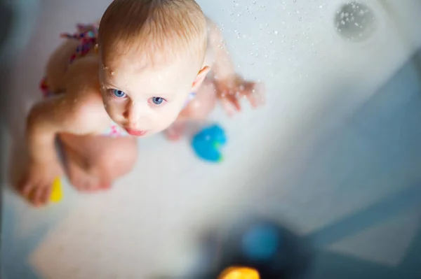 Blauäugiges Baby im Badeanzug genießt Wasser in der Dusche — Stockfoto