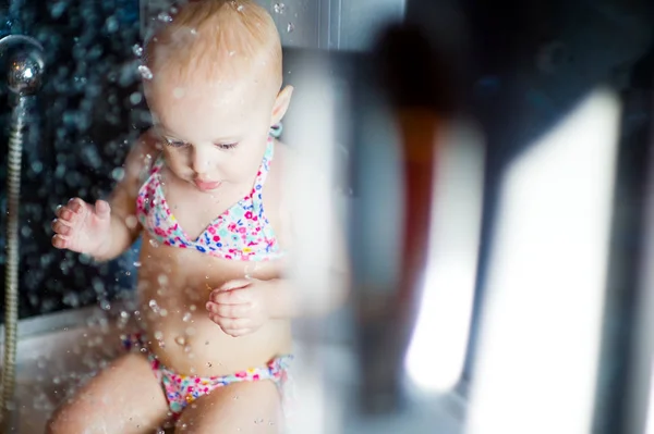 Little girl sits in a shower cabin — Stock Photo, Image