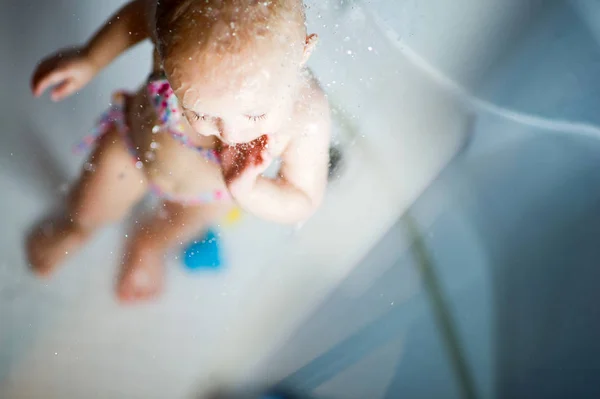 Kleines Mädchen im Badeanzug genießt Wasser in der Dusche — Stockfoto