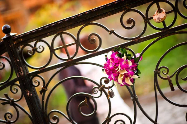 Bir düğün buketi arkasında yeni evliler defokus el ele tutuşan zarif bir çit içine yerleştirilir. Tahıl