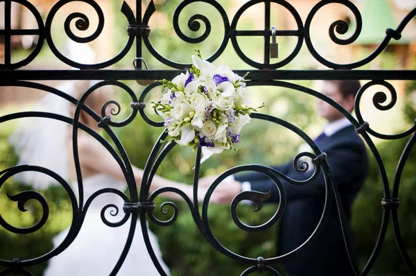 Bir gelin buketi arkasında yeni evliler defokus el ele tutuşan zarif bir çit, içine yerleştirilir. Tahıl