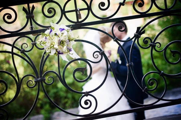 Bir gelin buketi zarif bir çit içine yerleştirilir, hangi yeni evliler öpücük. Tahıl