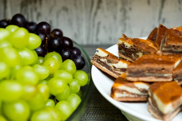 Teller mit geschnittenem Kuchen und Teller mit Trauben in Nahaufnahme — Stockfoto