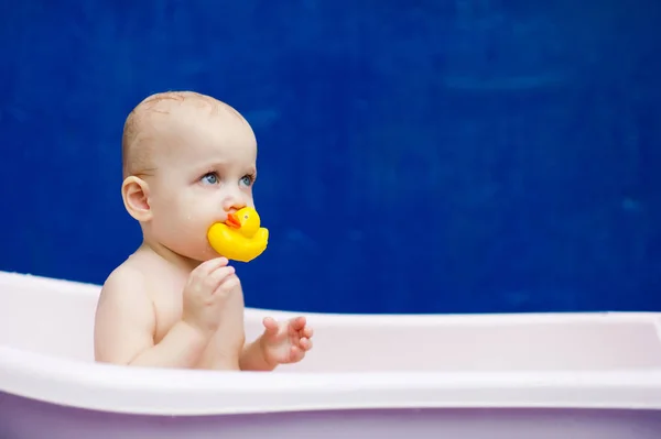 Babymädchen hält sich im Badezimmer eine Gummiente in die Zähne — Stockfoto