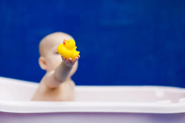 Das Kind hält dem Betrachter eine gelbe Spielzeugente hin — Stockfoto