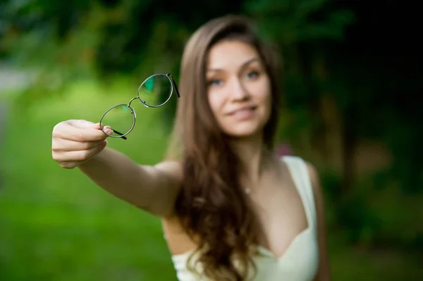 Jovem menina segura óculos de visão na frente de seus olhos e mantém-los para a frente — Fotografia de Stock