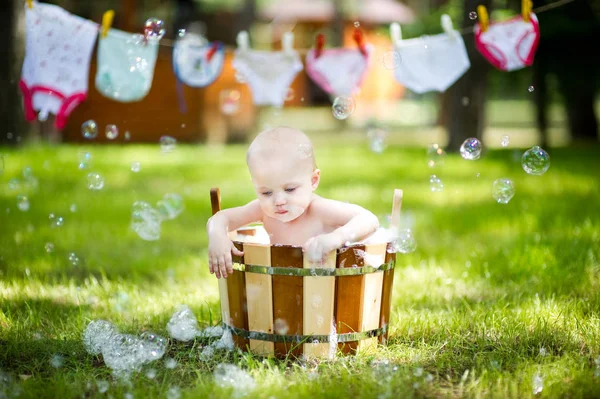 Bambino che si diverte in un bagno di legno con schiuma e bolle — Foto Stock