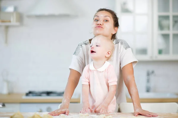 Mama i córka są barwione w mąkę w kuchni podczas gry i wyglądają śmieszne — Zdjęcie stockowe