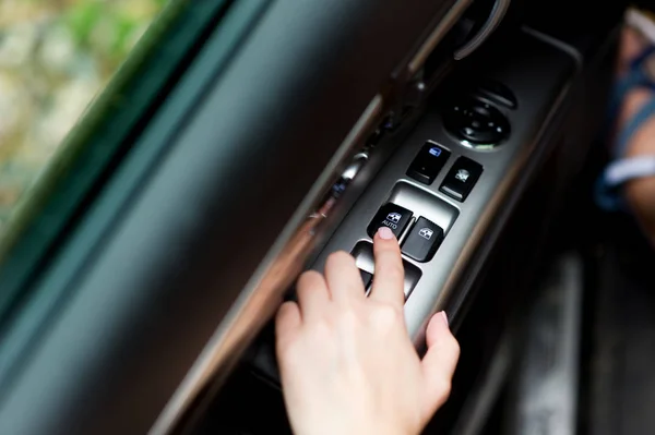 Girl is going to lower the glass in the car with the power window button — Stock Photo, Image