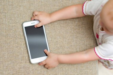 bebek kanepeden kilitli bir akıllı telefon alır