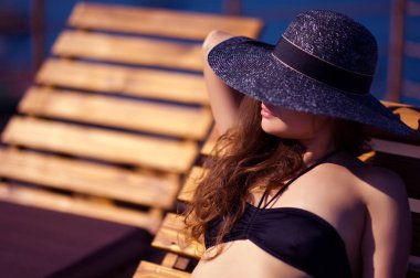 şapkalı genç kadın güneşlenin