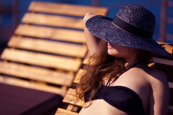 şapkalı genç kadın güneşlenin