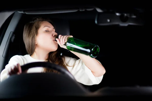 Ung kvinna kör en bil på natten och dricker alkohol under körning. Kopiera utrymme — Stockfoto