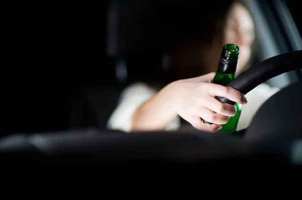 Main avec une bouteille d'alcool sur le volant, fille déconcentrée endormie au volant. espace de copie — Photo