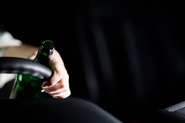 Пролитая бутылка алкоголя, рука водителя и руль. копировальное пространство — стоковое фото