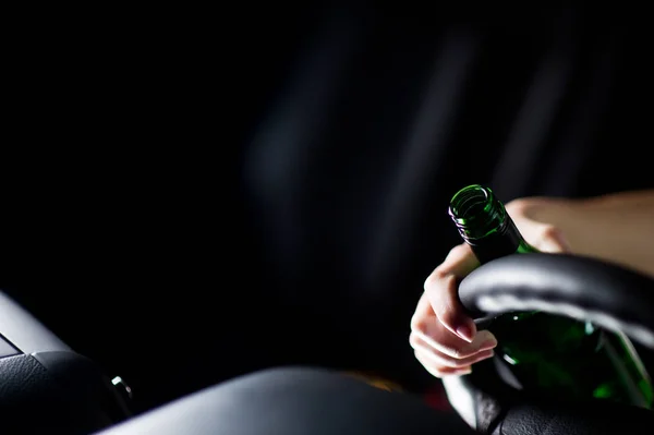 Close-up gemorste fles alcohol, bestuurders hand en stuurwiel. ruimte kopiëren — Stockfoto