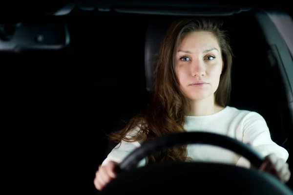 Menina segura o volante em um carro e olha para a câmera. espaço de cópia — Fotografia de Stock