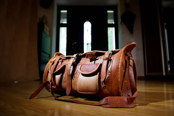 Una bolsa de viaje de cuero se encuentra cerca de la puerta principal de la casa — Foto de Stock