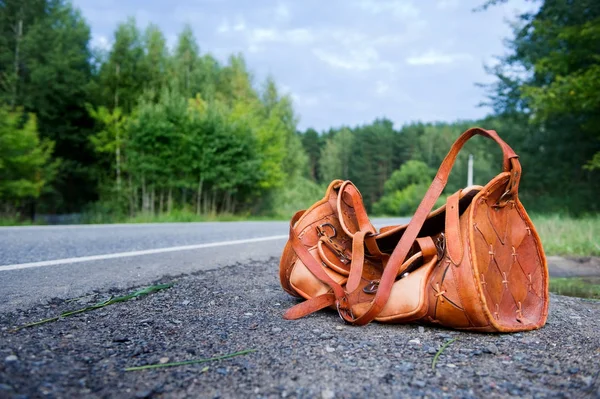 Bolsa de couro laranja no lado de uma estrada rural em um dia de verão. Ângulo largo — Fotografia de Stock