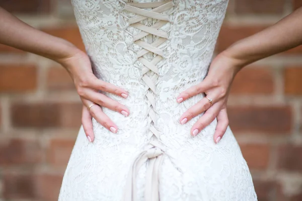 the bride s hands with bright manicure lie on the lower back, a look through the veil