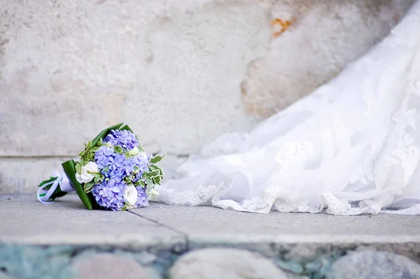 Der Strauß liegt auf der Pflasterplatte neben der Schleppe des Brautkleides — Stockfoto