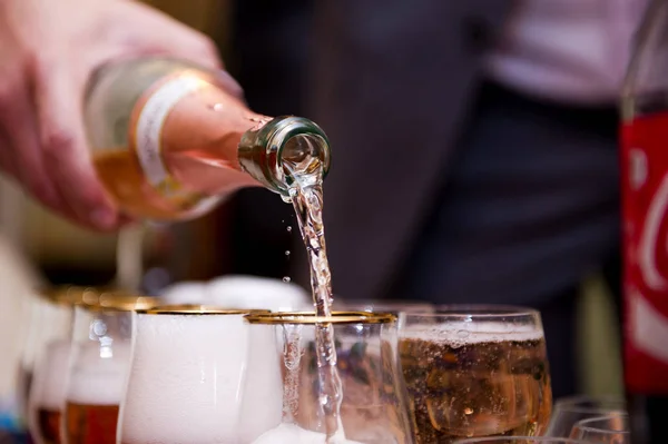 Champagne d'une bouteille est versé dans un gobelet de verre . — Photo