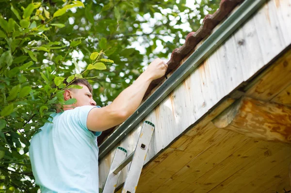 Master werkt. de eigenaar concentreert zich op het dak van zijn huis om de goot te meten — Stockfoto