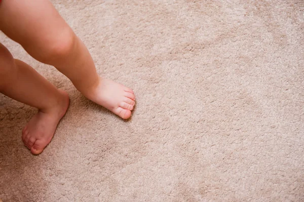 little feet of a child stand on the carpet