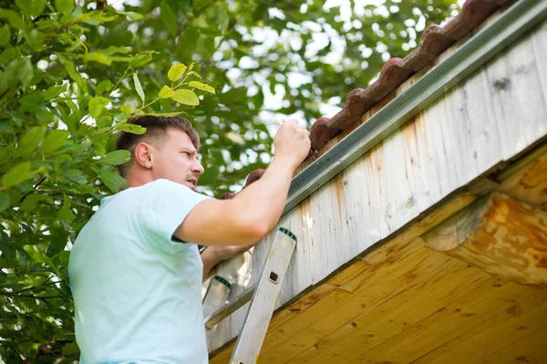 Master fungerar. den husägare koncentrerar sig på taket på sitt hus för att mäta rännstenen — Stockfoto